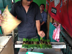 Orang sedang membakar otak-otak di depan restoran.